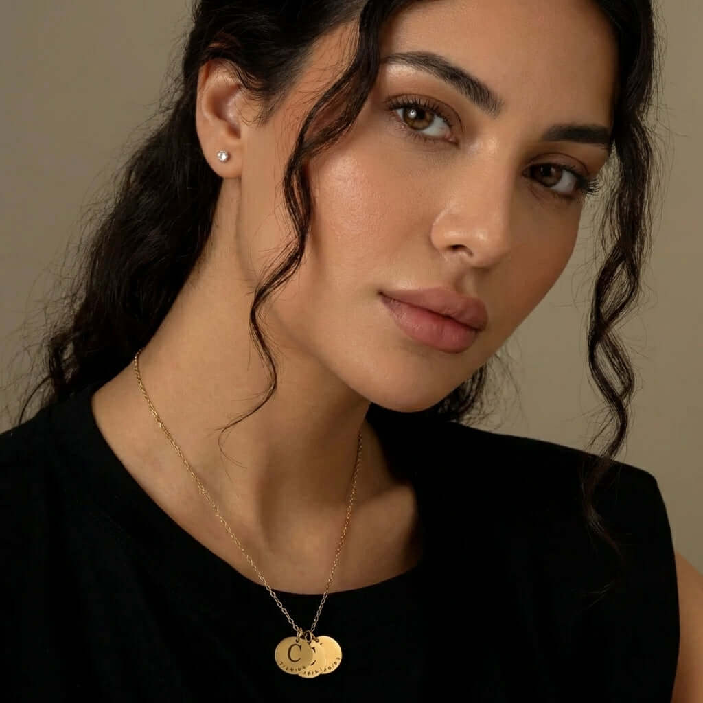 Close-up of woman wearing AUREATE Date & Initial Charm Necklace, featuring personalized charms and a stylish design.