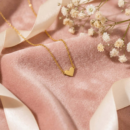 Classic Heart Pendant Necklace by AUREATE displayed elegantly on soft pink fabric with delicate flowers.