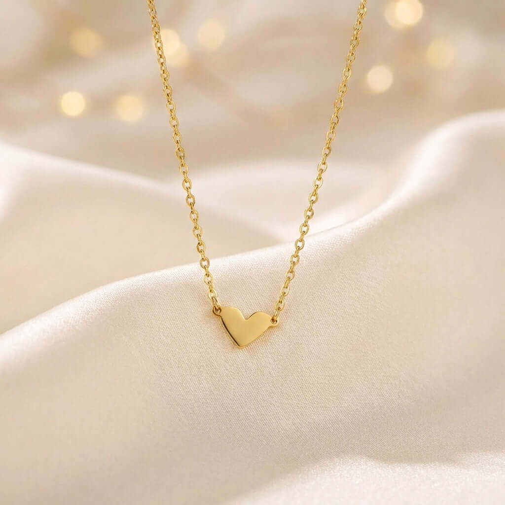 Classic Heart Pendant Necklace by AUREATE, dainty gold heart necklace on soft fabric background.