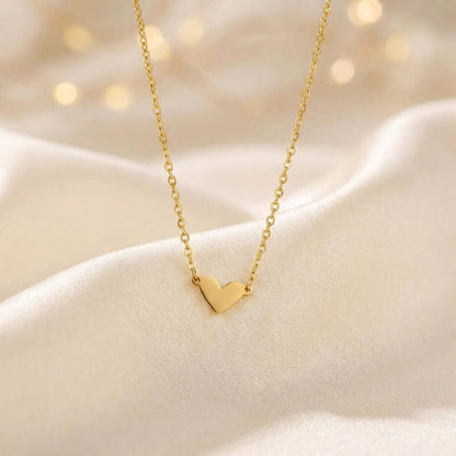 Classic Heart Pendant Necklace by AUREATE, dainty gold heart necklace on soft fabric background.