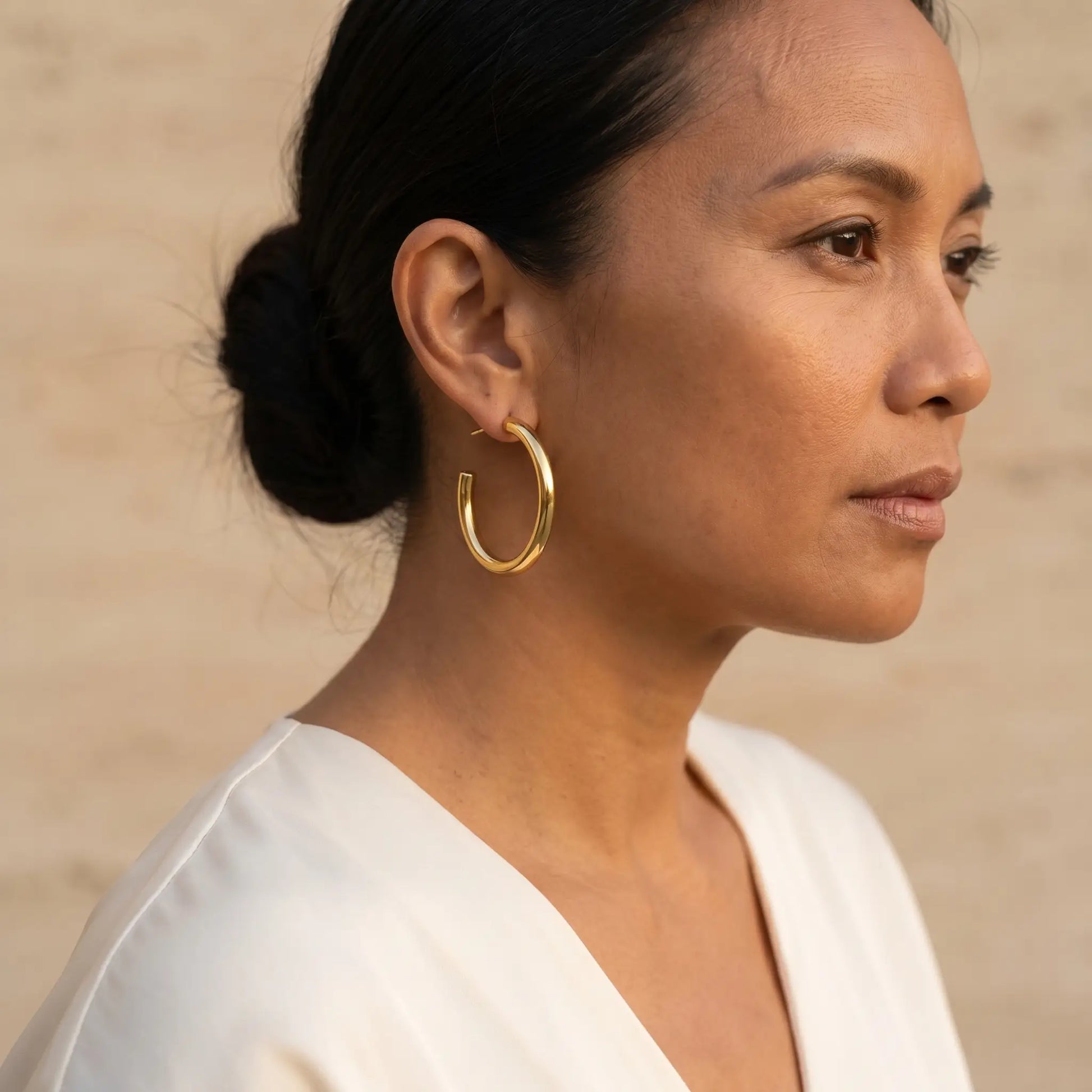 Woman wearing Chunky Gold Hoop Earrings - studio three-quarter profile editorial