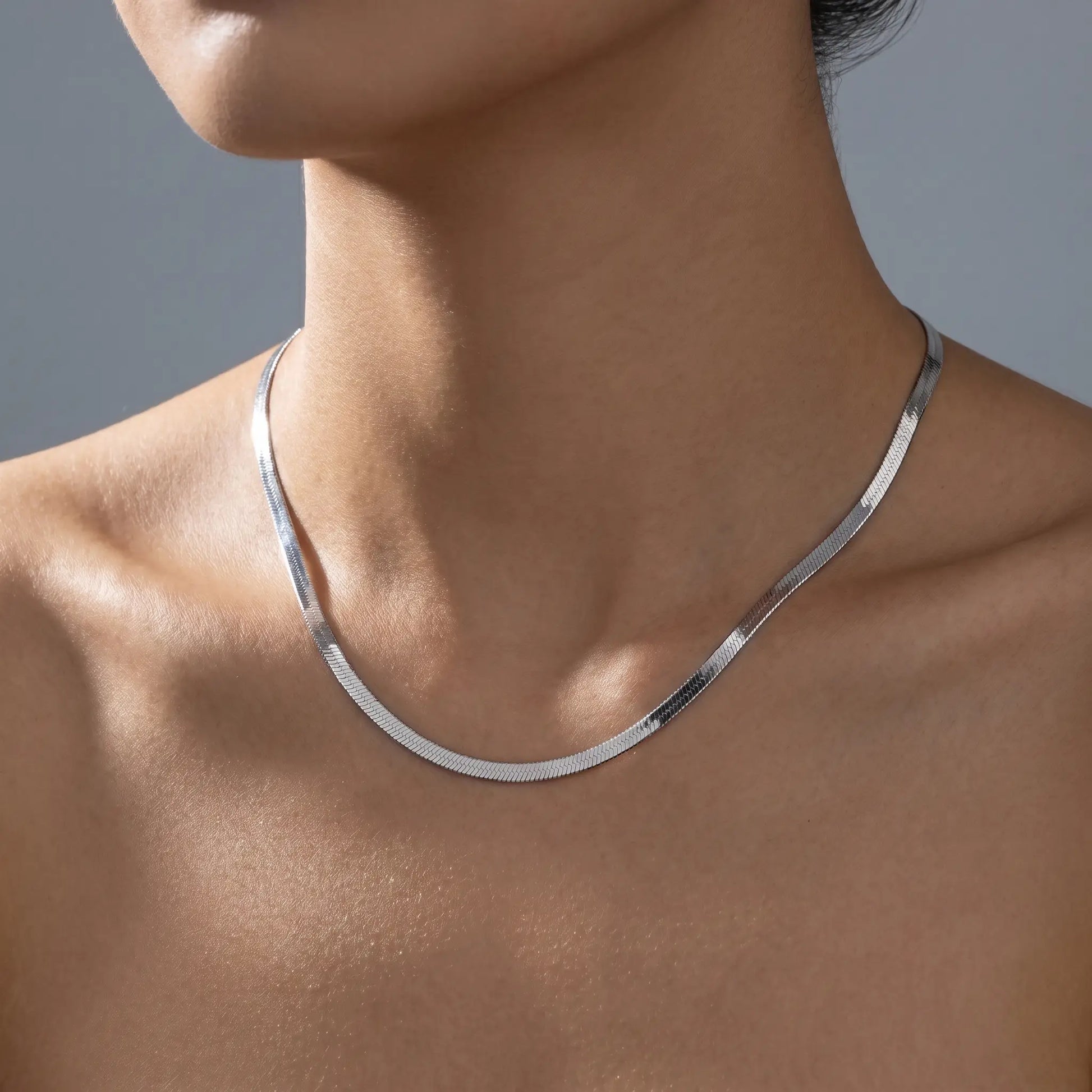 AUREATE 5mm Herringbone silver chain on woman's décolleté studio close-up