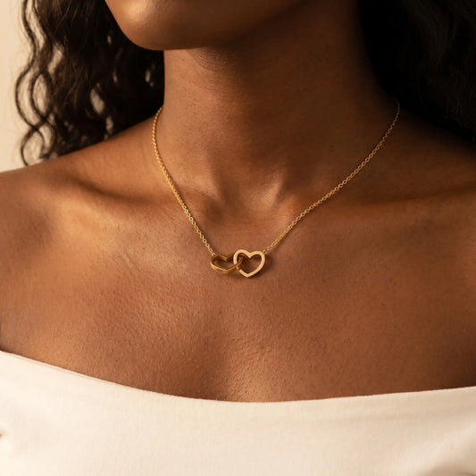 Engraved Double Heart Pendant 18K Gold worn close-up by African American woman, two interlocked open-outline hearts at collarbone with personalized name engraving by AUREATE