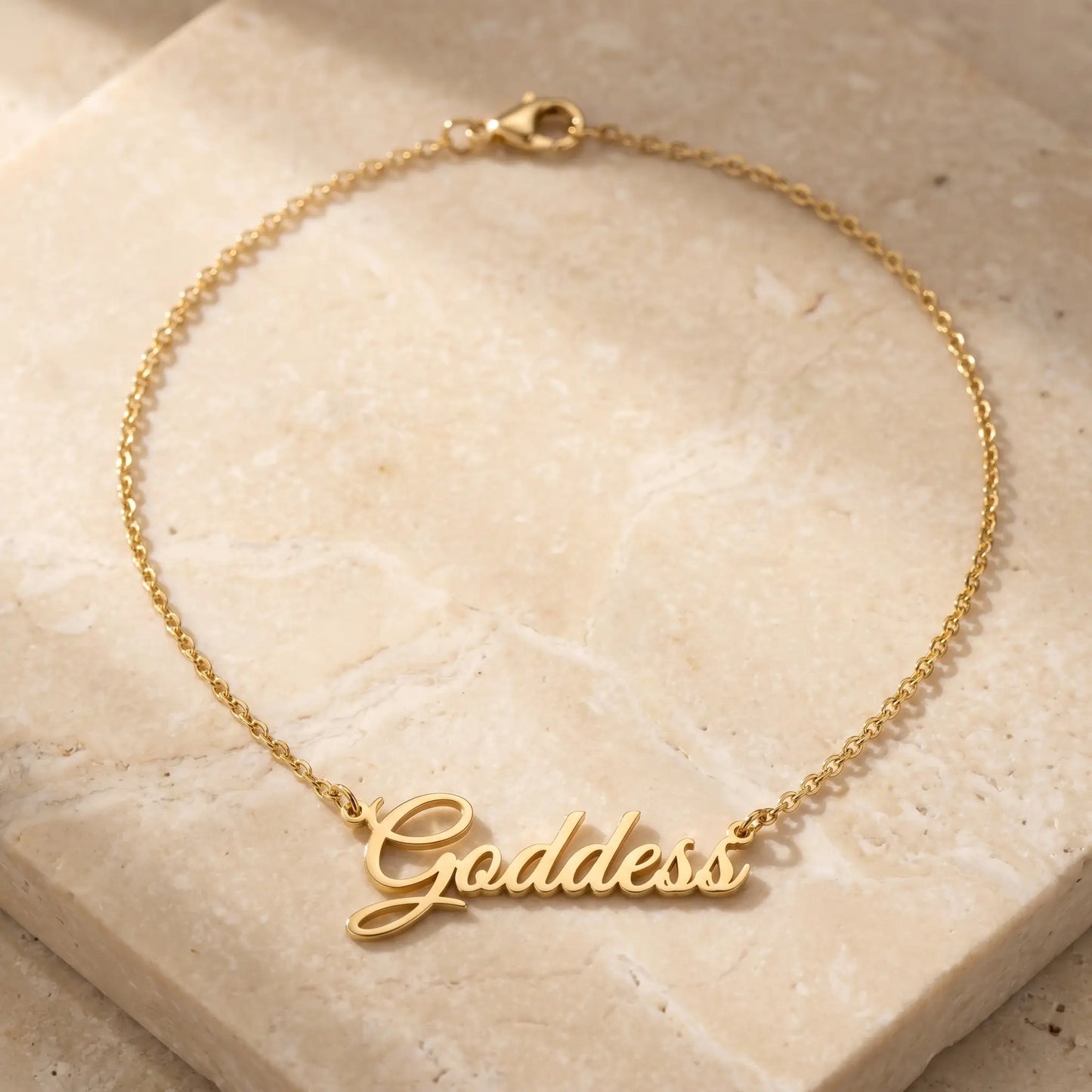 Personalized Script Name Chain 18K gold cursive nameplate packshot on travertine by AUREATE