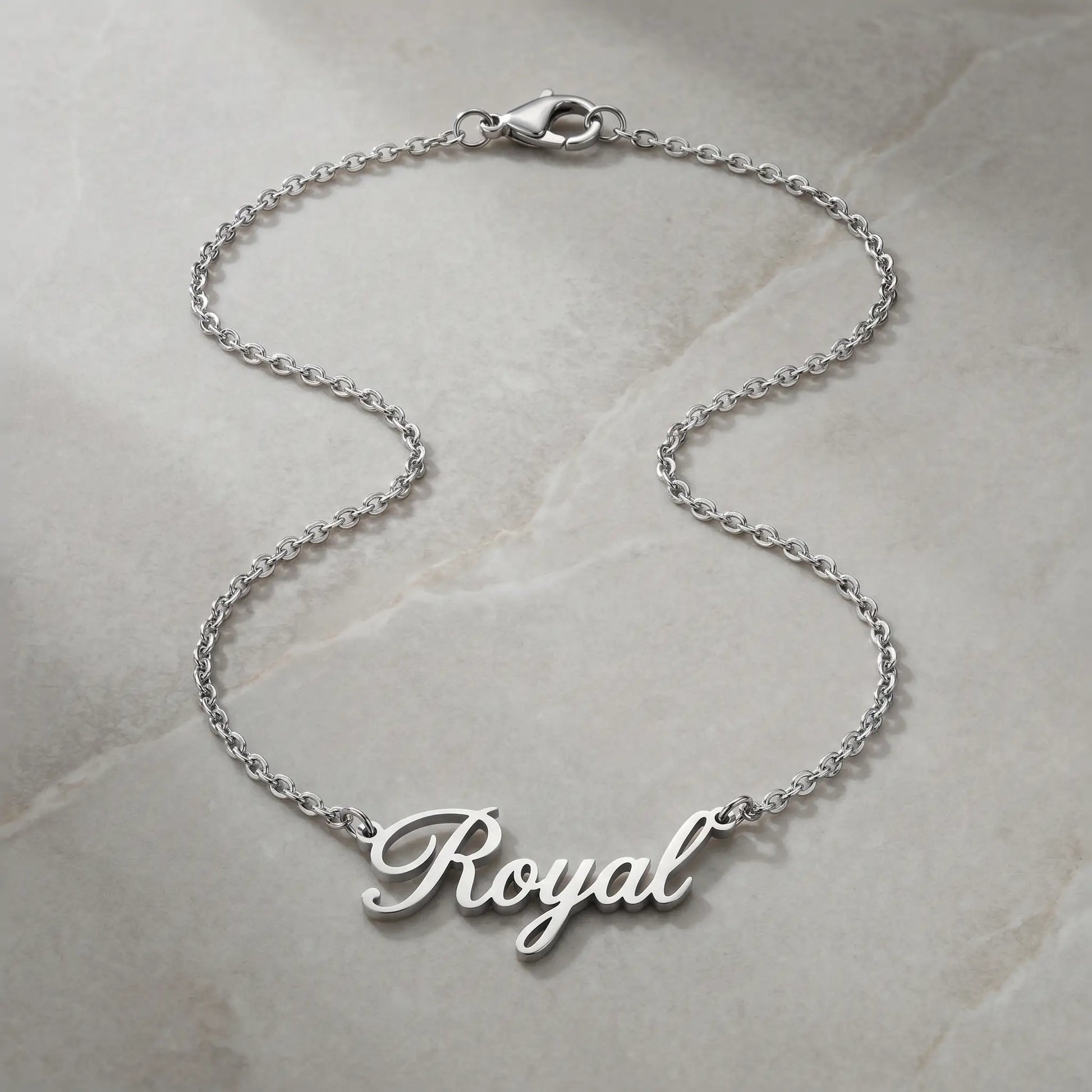 Personalized Script Name Chain silver tone cursive nameplate packshot on cool stone by AUREATE