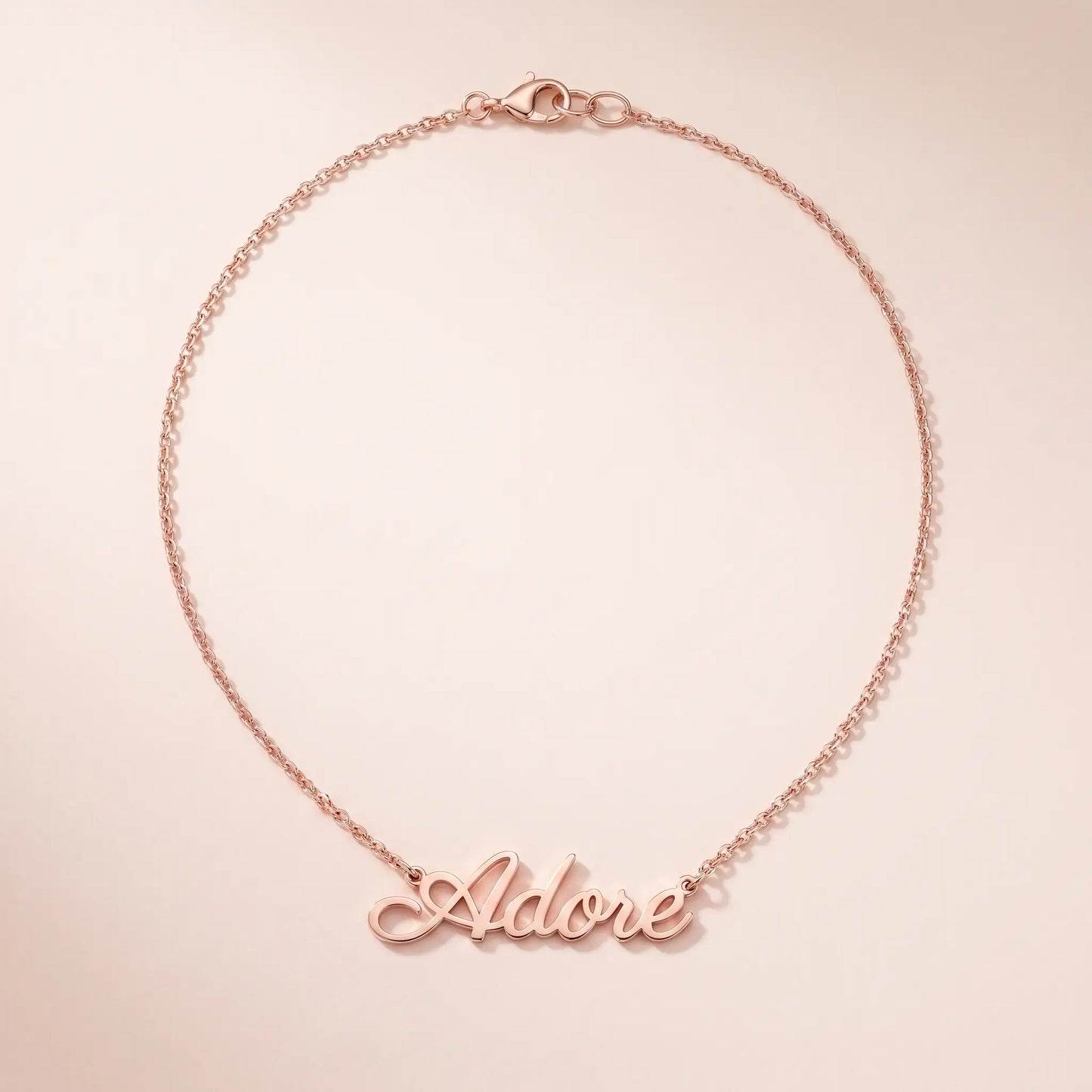 Personalized Script Name Chain rose gold cursive nameplate packshot on blush cream by AUREATE