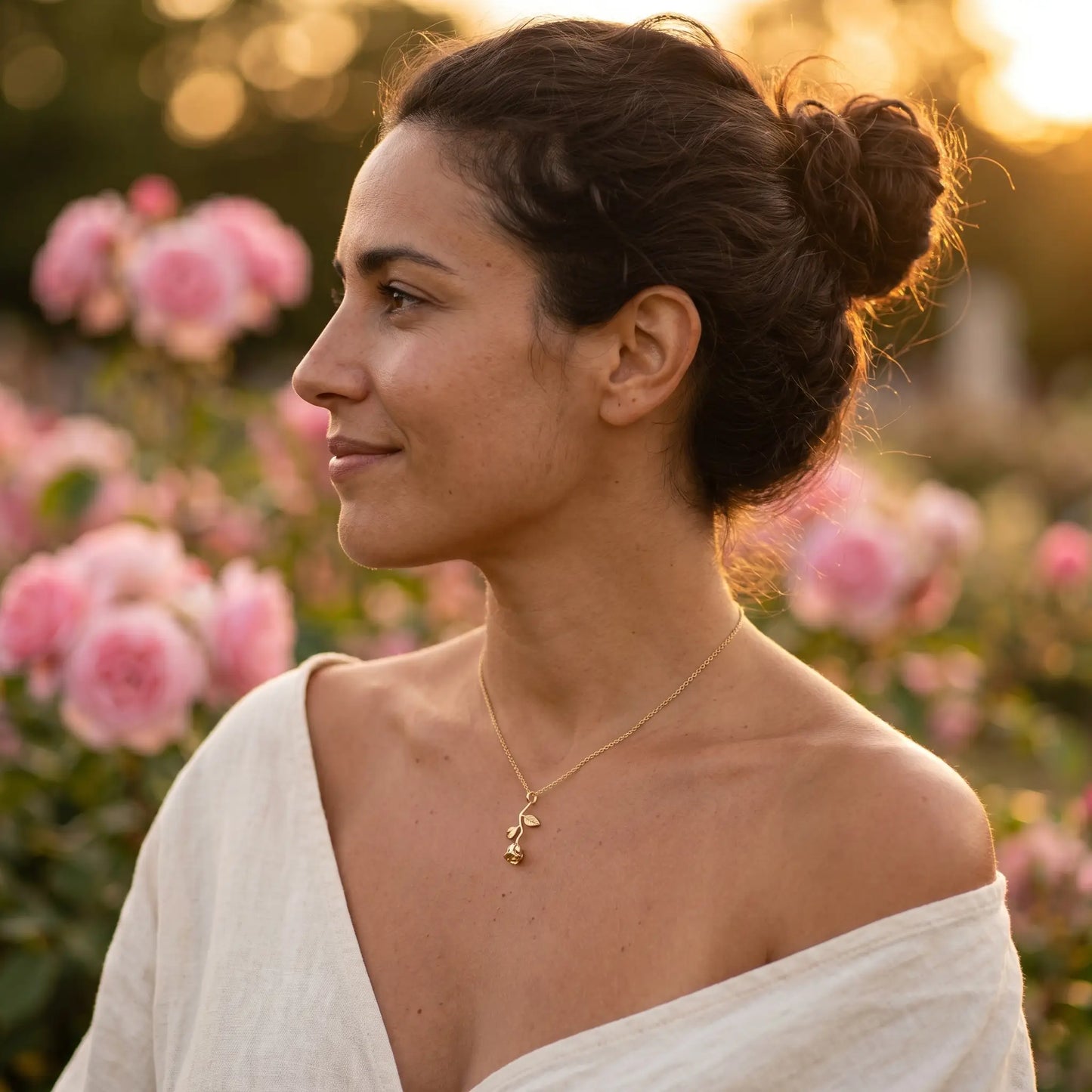 AUREATE Rose Flower Charm Pendant 18K Gold profile in a rose garden at golden hour — quiet contented subtle smile, romantic feminine aesthetic.