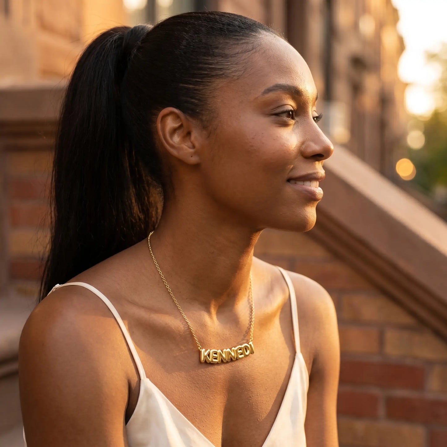 AUREATE Bubble Letter Name Chain 18K gold KENNEDI profile subtle smile editorial Brooklyn brownstone