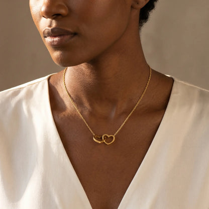 Engraved Double Heart Pendant 18K Gold worn 3/4 profile by Ethiopian woman in ivory silk blouse, mature serene elegance with personalized engraving by AUREATE
