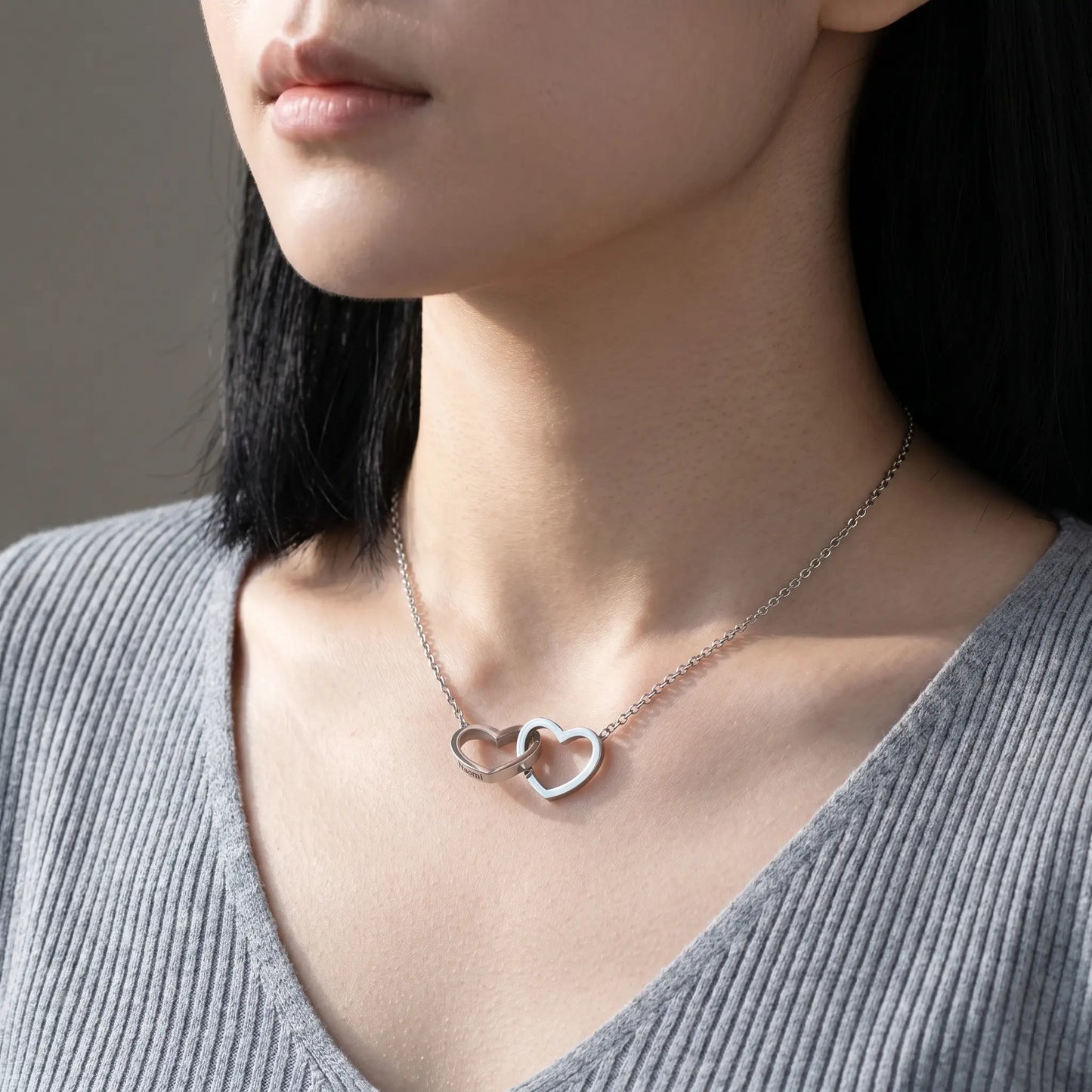 Engraved Double Heart Pendant Silver Stainless Steel worn close-up by Korean woman in dove-grey ribbed knit, two interlocked hearts personalized engraving by AUREATE