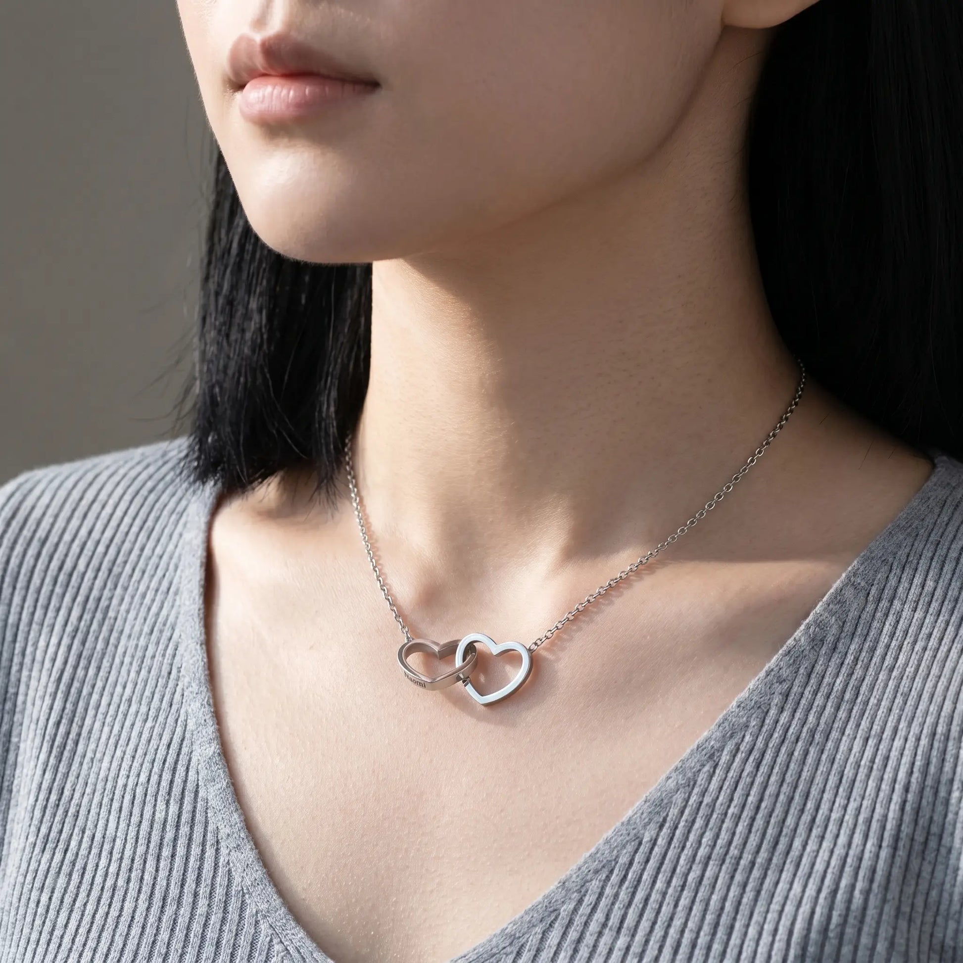 Engraved Double Heart Pendant Silver Stainless Steel worn close-up by Korean woman in dove-grey ribbed knit, two interlocked hearts personalized engraving by AUREATE