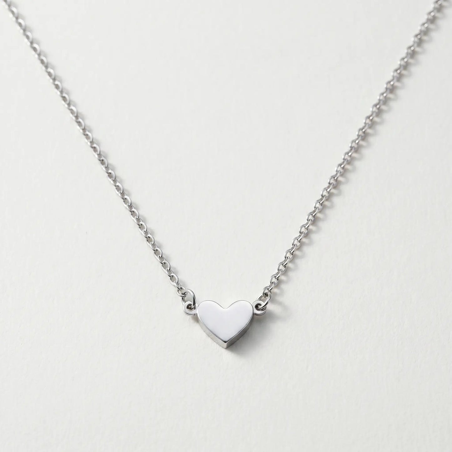 Timeless Heart Pendant Chain by AUREATE in silver tone packshot V-shape symmetric drape on cool ivory
