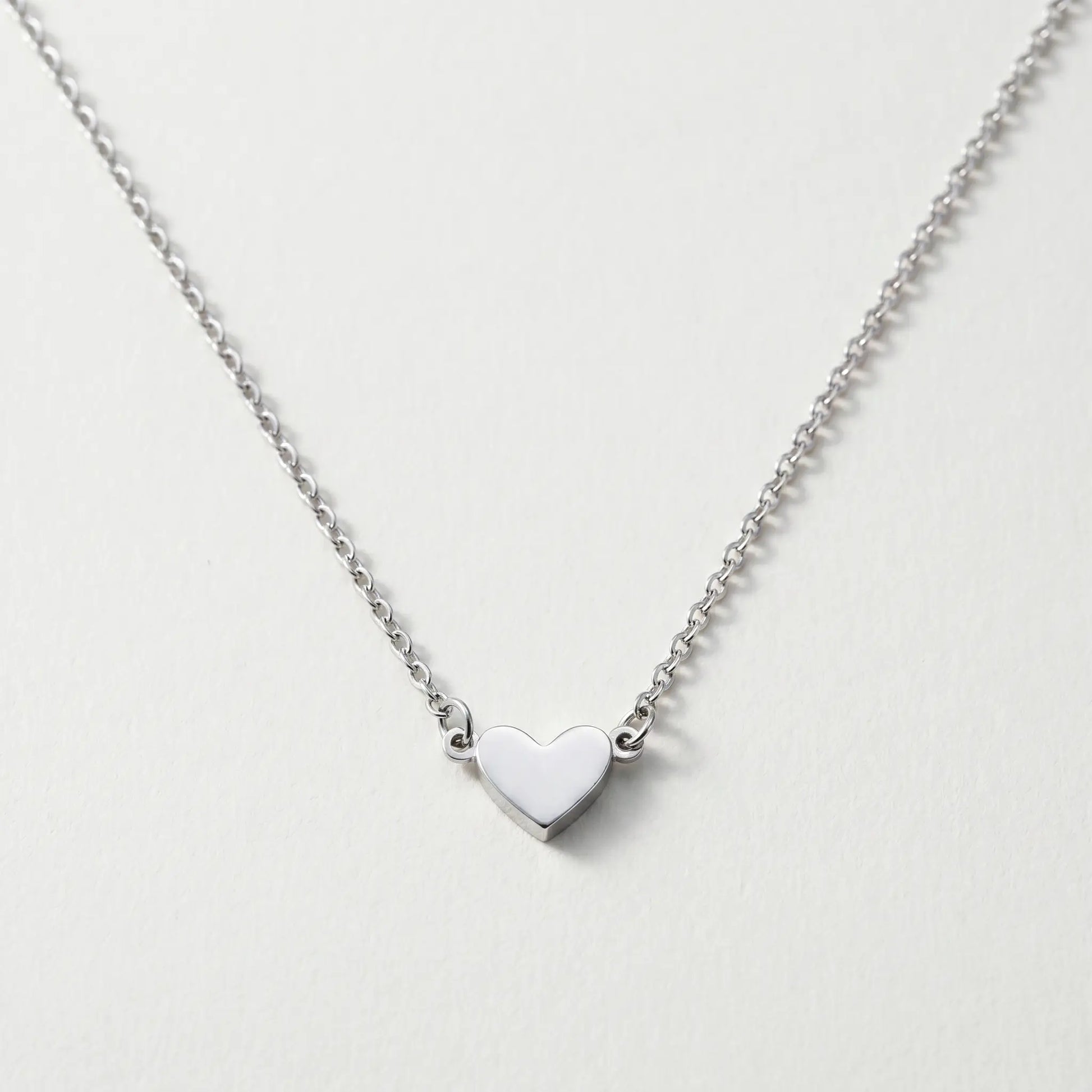 Timeless Heart Pendant Chain by AUREATE in silver tone packshot V-shape symmetric drape on cool ivory