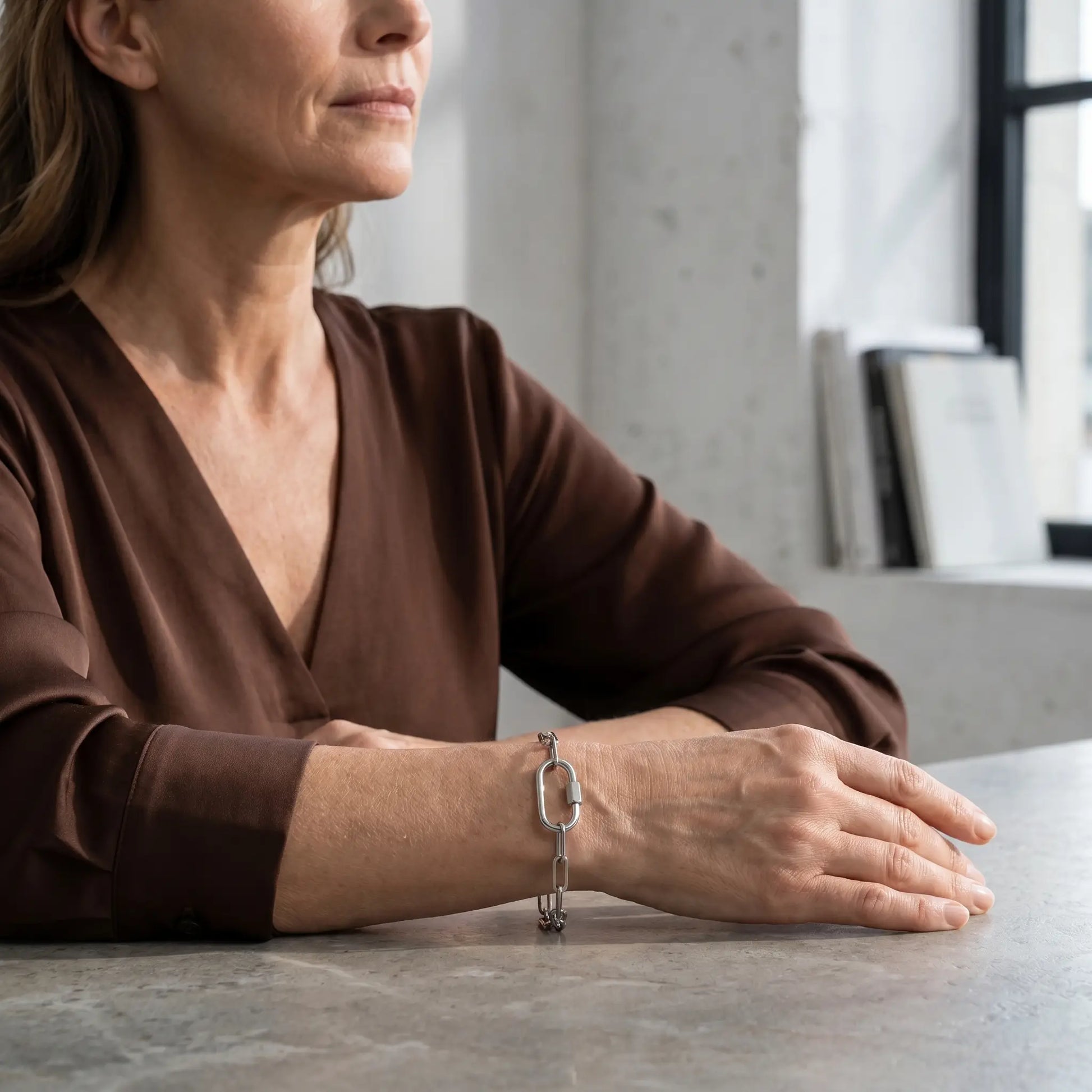 Silver paperclip bracelet on mature woman's wrist - quiet luxury editorial