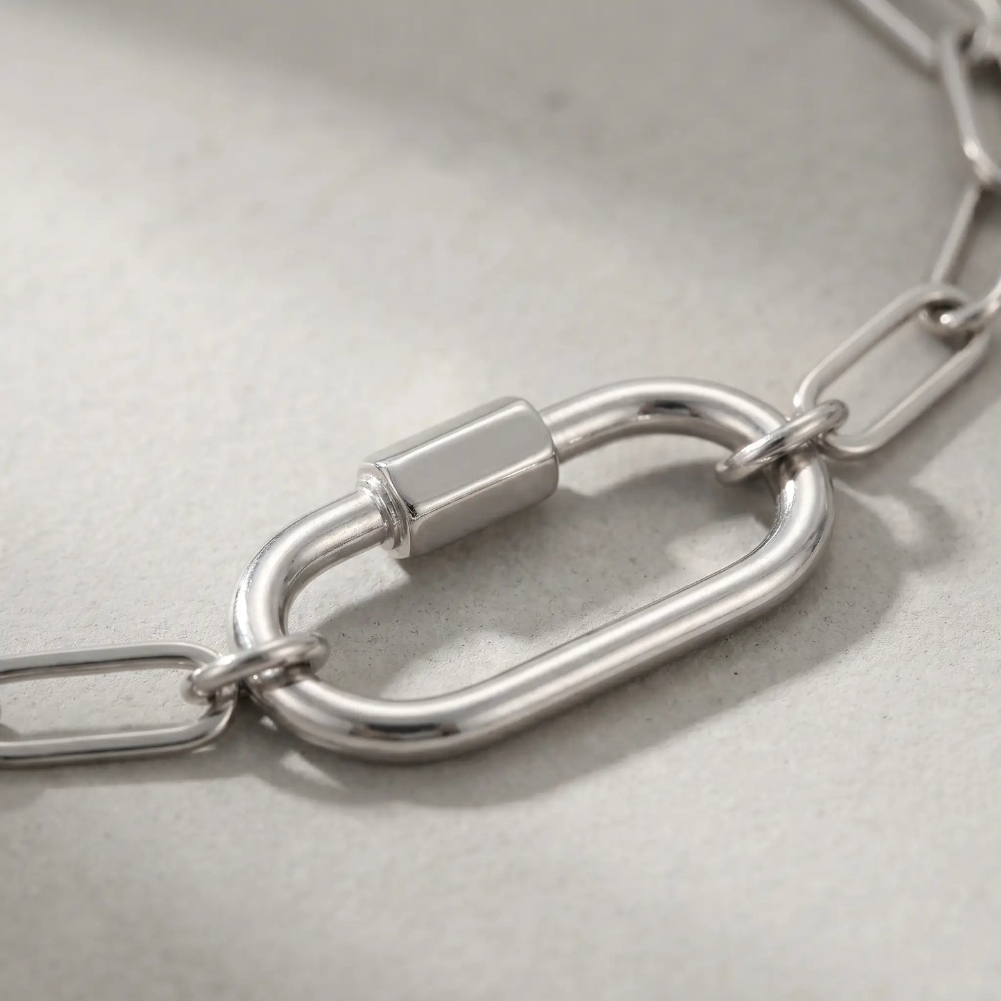 Silver paperclip bracelet macro detail oval carabiner lock pendant