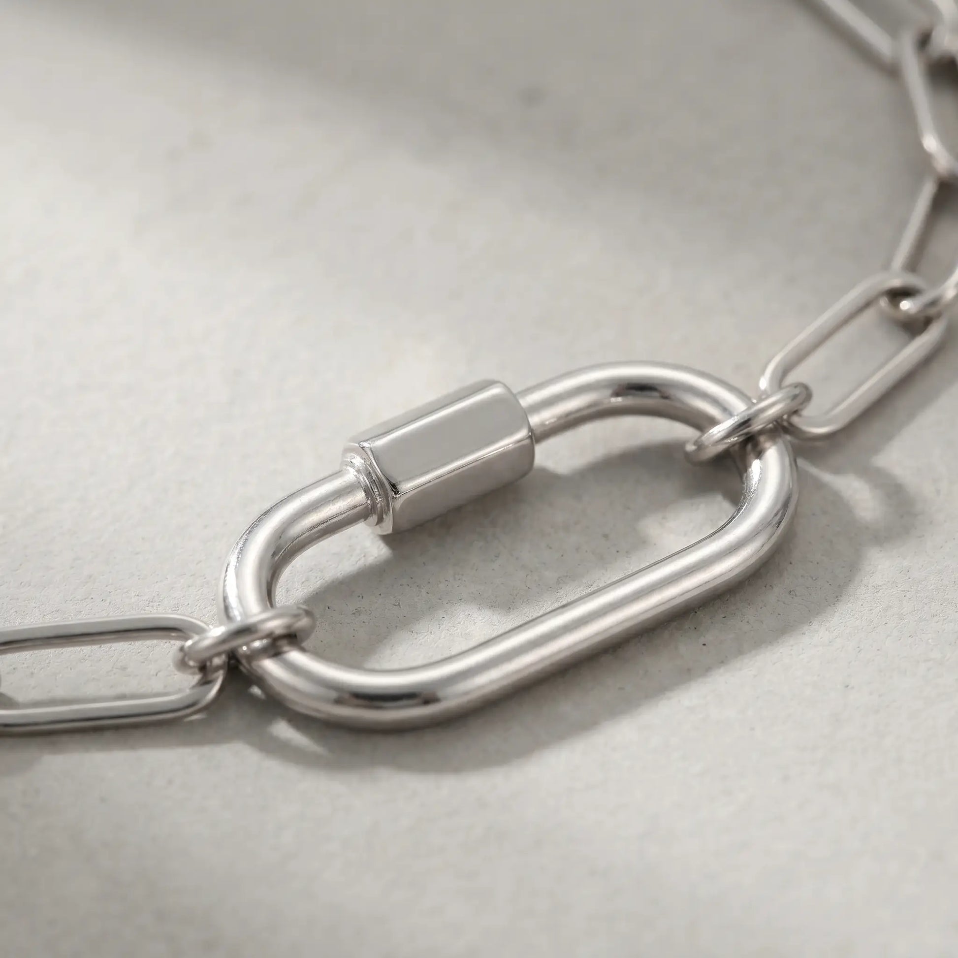 Silver paperclip bracelet macro detail oval carabiner lock pendant