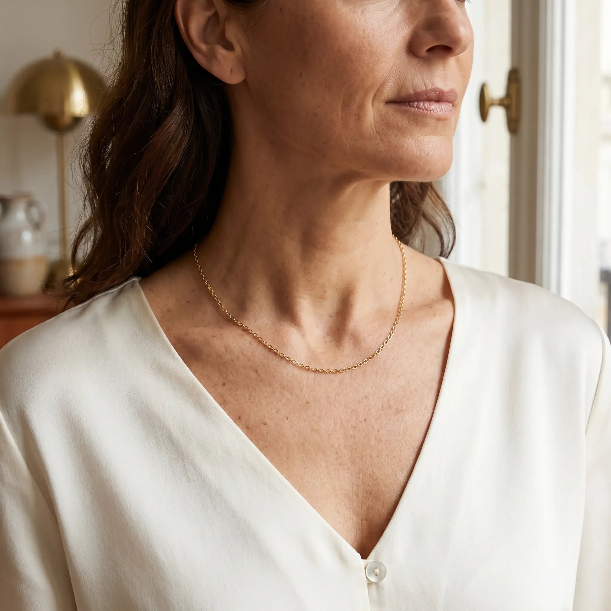 Gold dainty necklace worn three quarter profile mature elegance