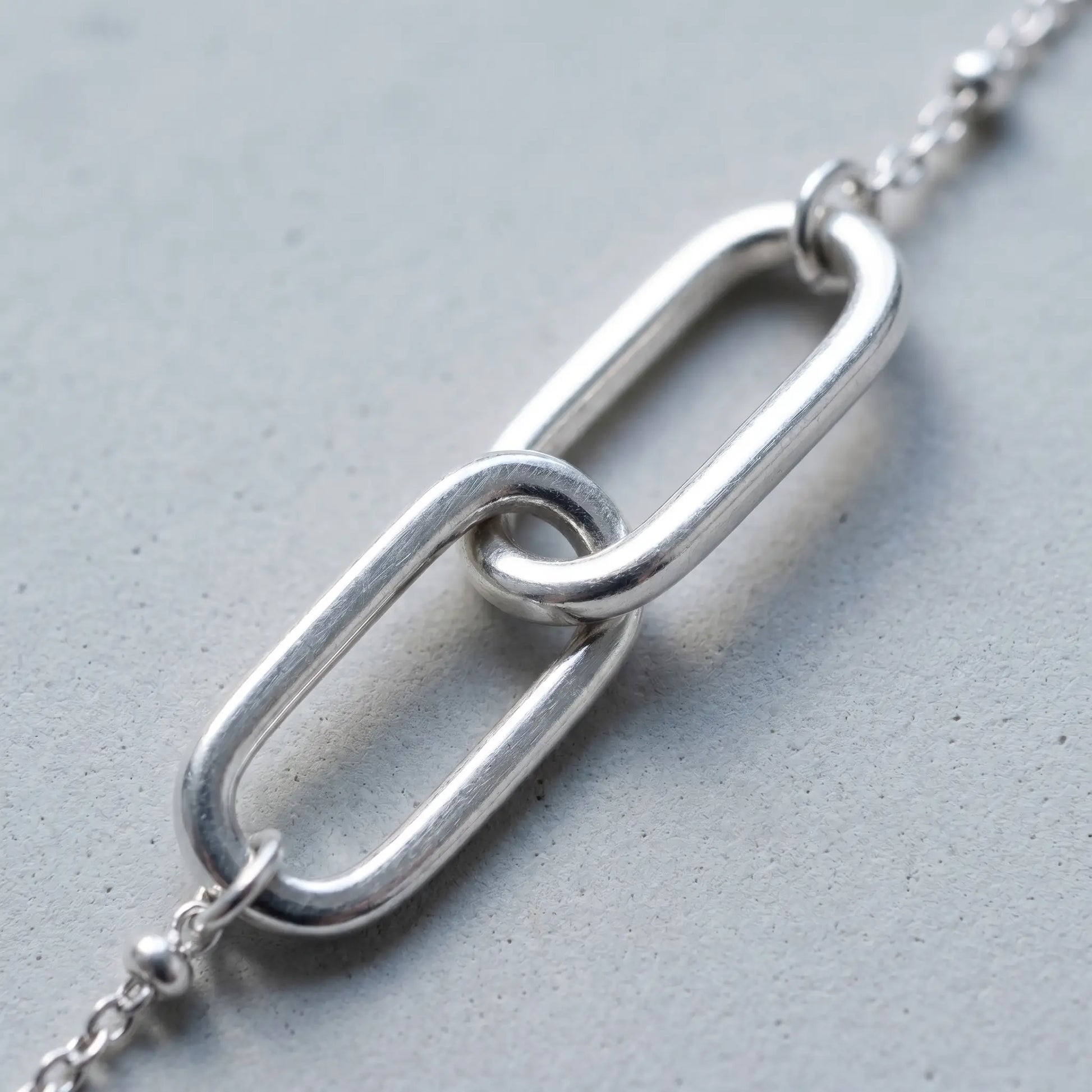 Linked Loop Necklace silver tone macro detail interlocked loops concrete