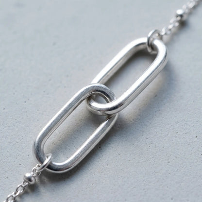 Linked Loop Necklace silver tone macro detail interlocked loops concrete