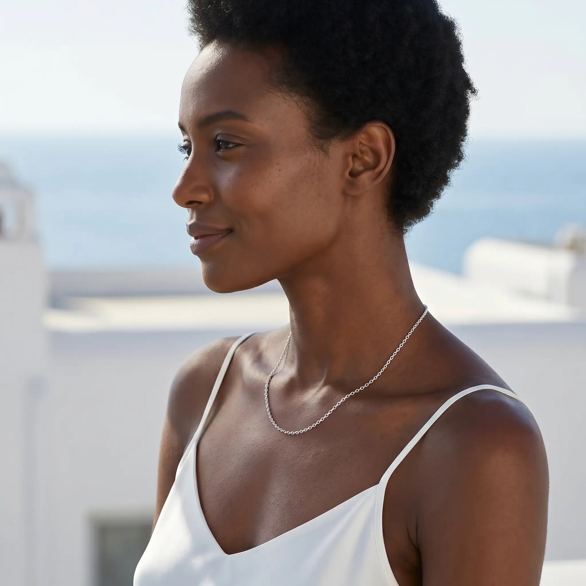 Silver collarbone necklace profile subtle smile Mykonos rooftop