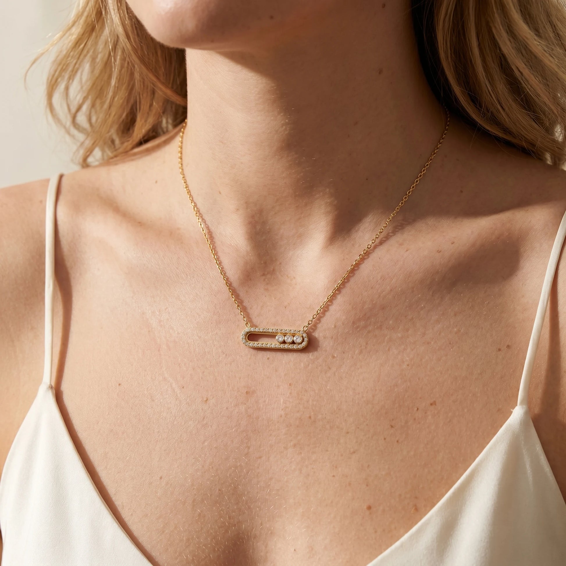 Trio Sliding Pavé minimalist gold necklace worn close-up on clavicle, paperclip pendant with 3 sliding CZ stones