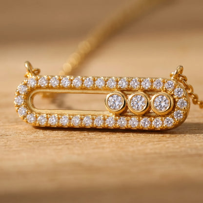Macro detail of gold pavé halo paperclip pendant with 3 bezel-set cubic zirconia stones