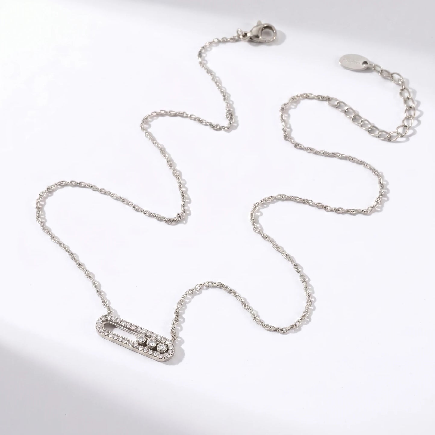 Silver paperclip pendant necklace flat lay packshot HORIZONTAL oval pendant 3 sliding CZ stones
