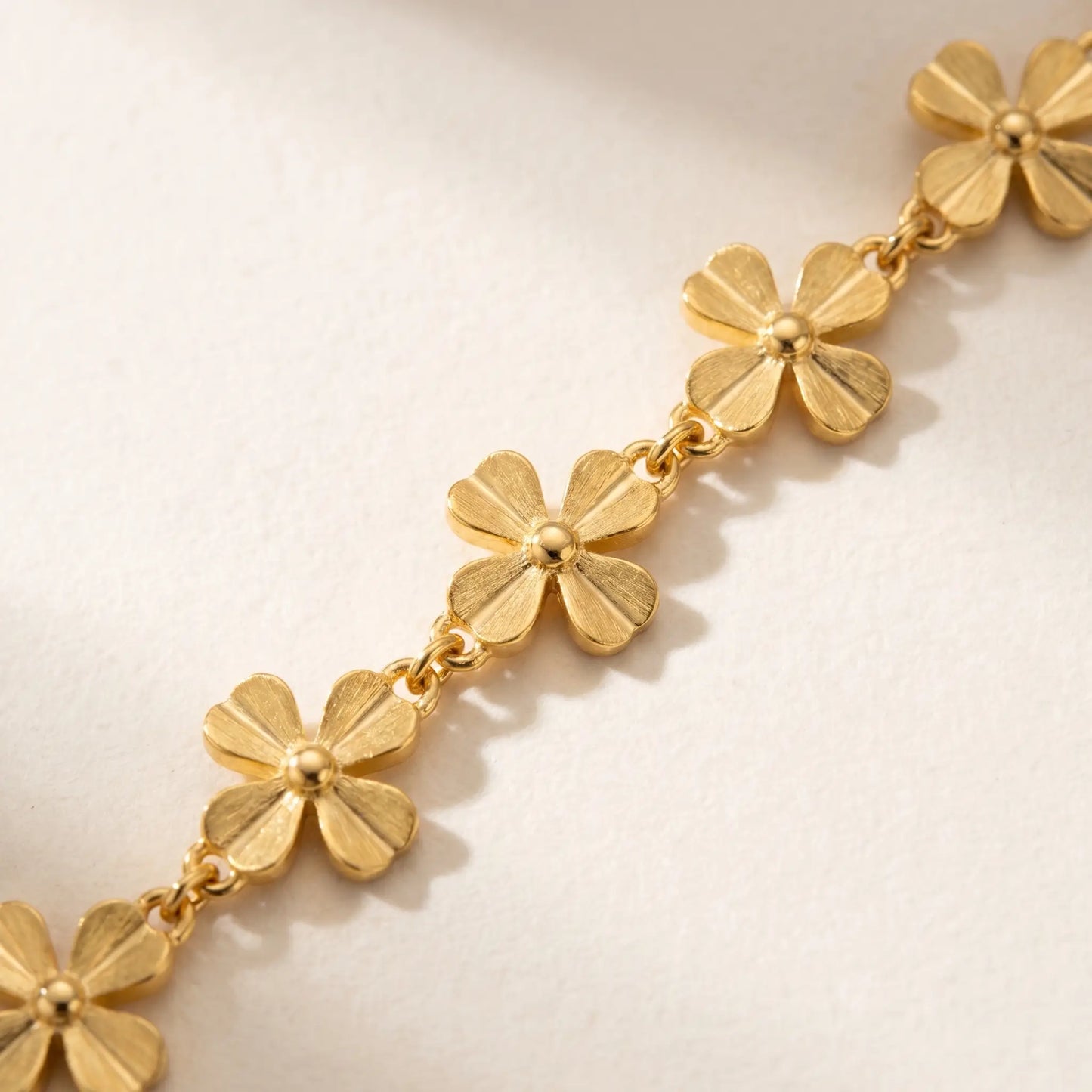 Macro detail of gold daisy flower link chain - 4-petal jewelry craftsmanship close-up