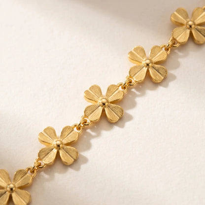 Macro detail of gold daisy flower link chain - 4-petal jewelry craftsmanship close-up