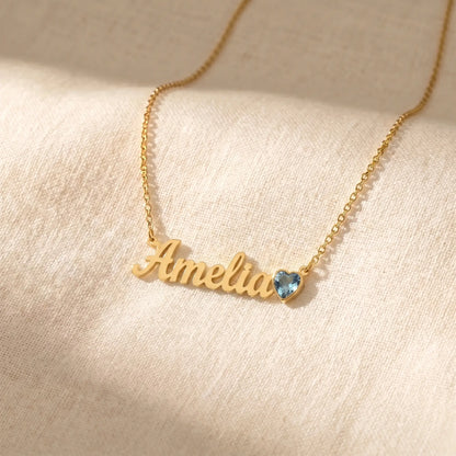 Birth Stone Letter Drop Strand 18K Gold flat-lay on cream linen with Amelia cursive name and March Aquamarine heart birthstone