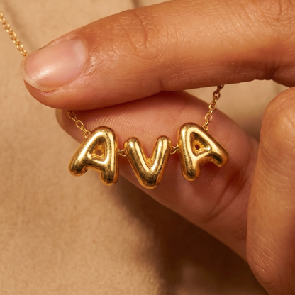 Gold puffy bubble-letter name necklace AVA held in hand, fine cable chain
