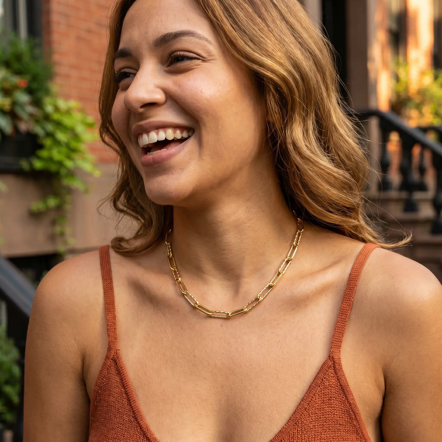 Mixed paperclip necklace gold lifestyle joy laugh — NYC brownstone golden hour terracotta tank
