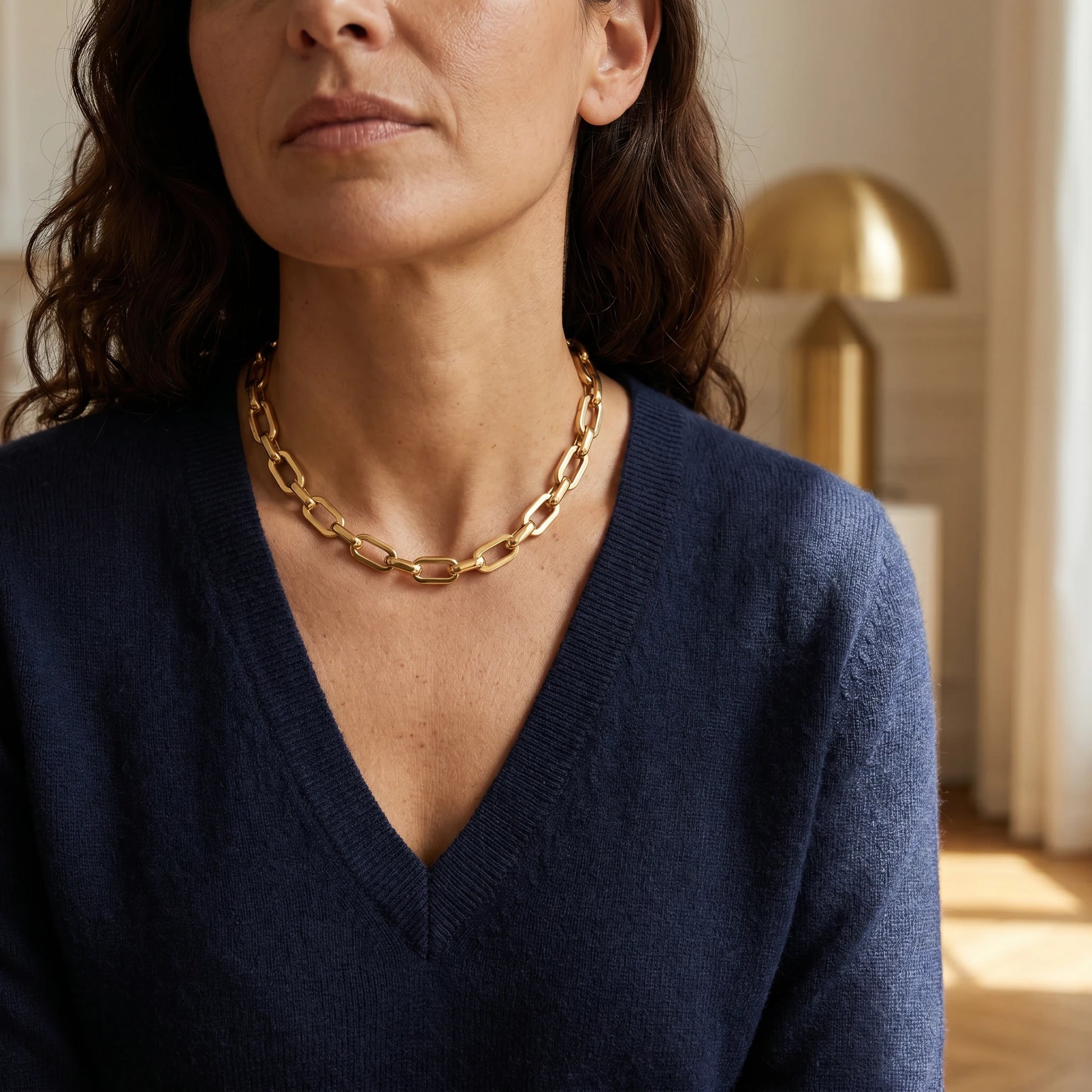 Mature woman wearing chunky gold cable chain necklace navy v-neck