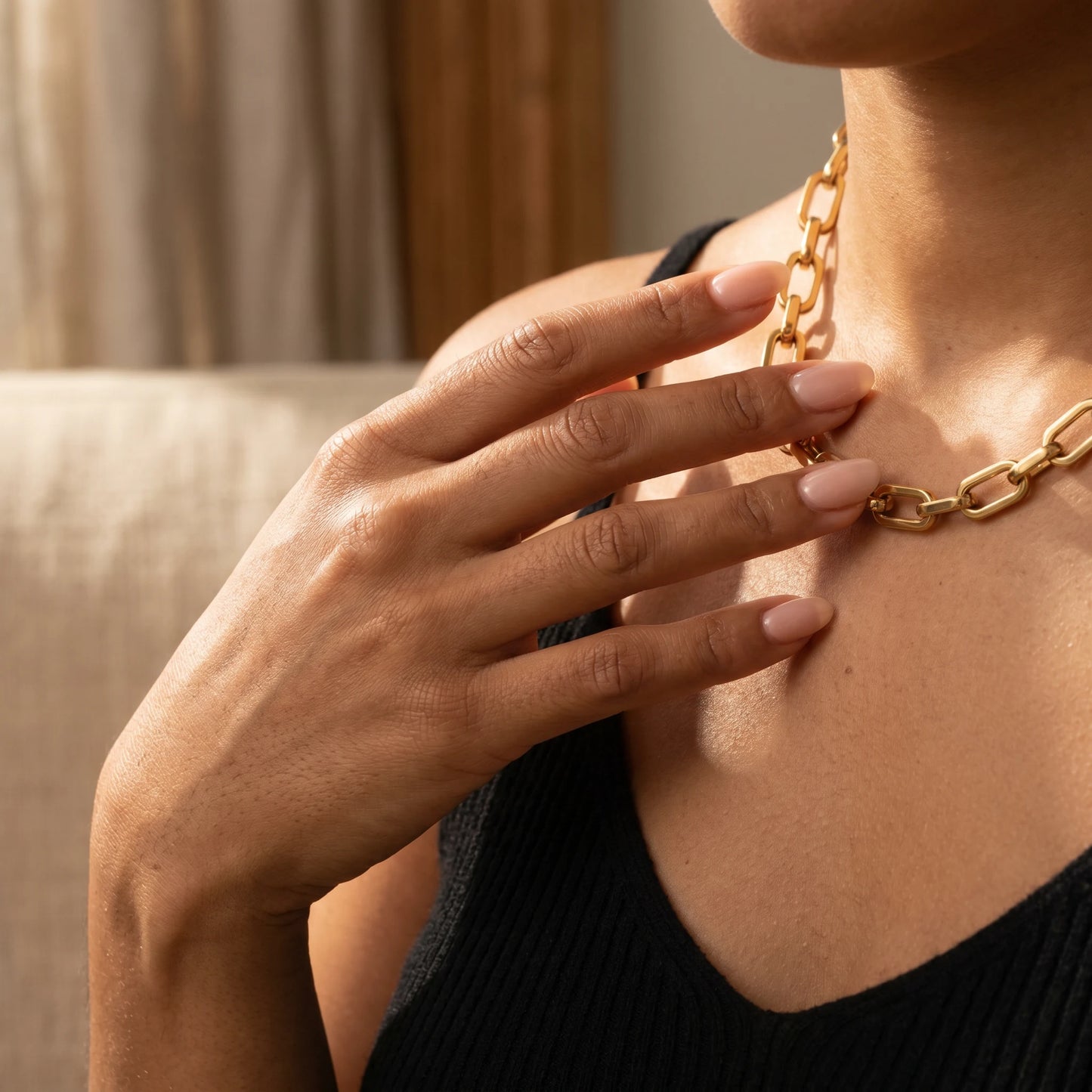Woman hand touching chunky gold cable chain necklace lifestyle