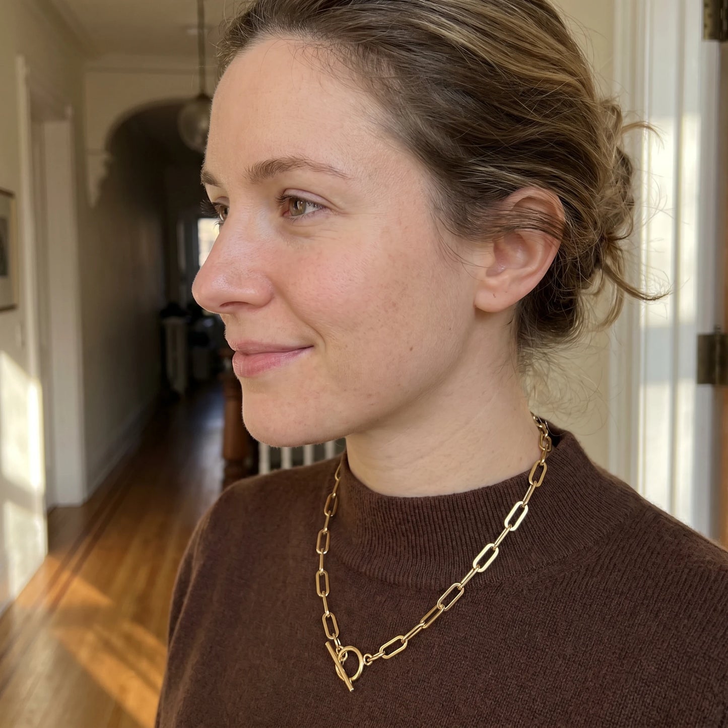 Paperclip toggle necklace gold side profile subtle smile downtown editorial