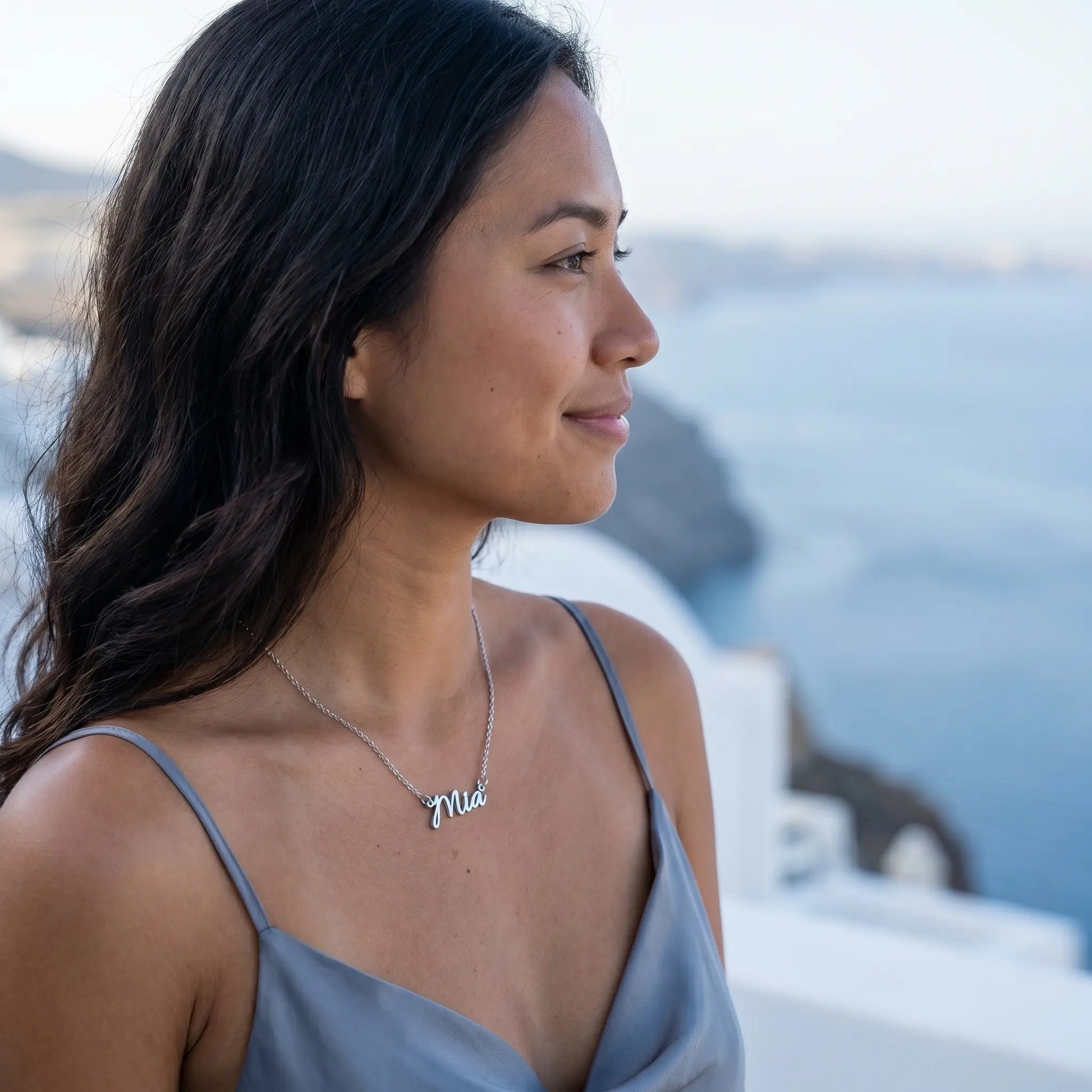 Personalised Plate Chain in 18K Gold by AUREATE worn by a woman with a scenic background.