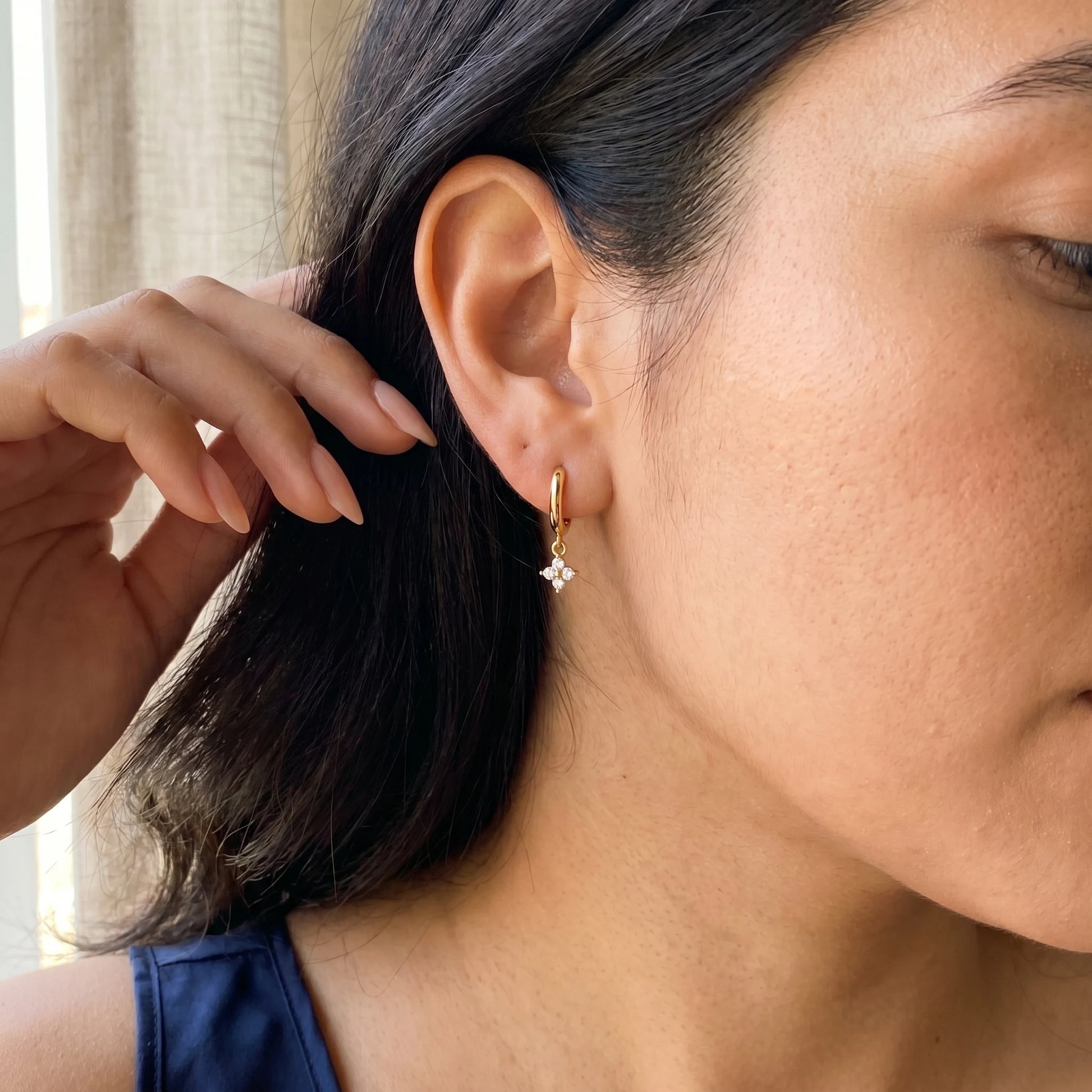 Gold petite clover huggie earrings lifestyle hand to ear