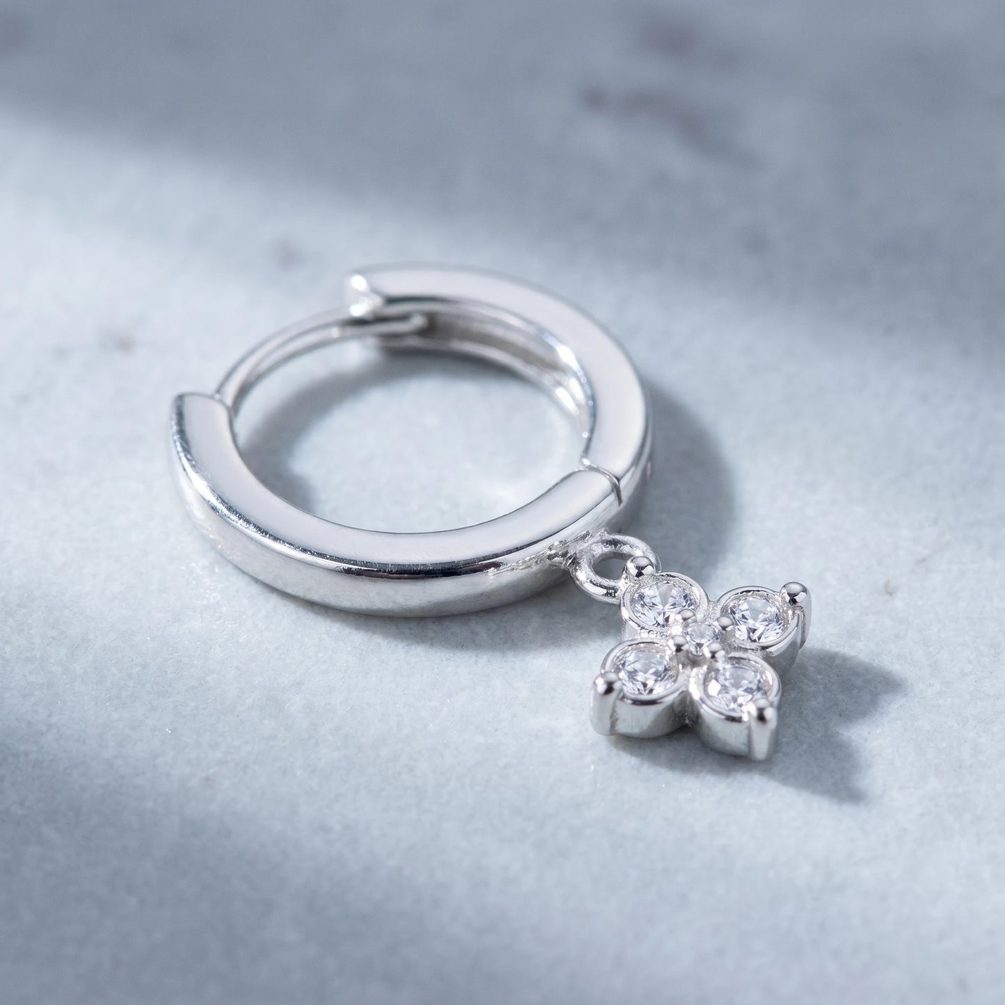 Silver petite clover huggie earring macro detail four CZ stones