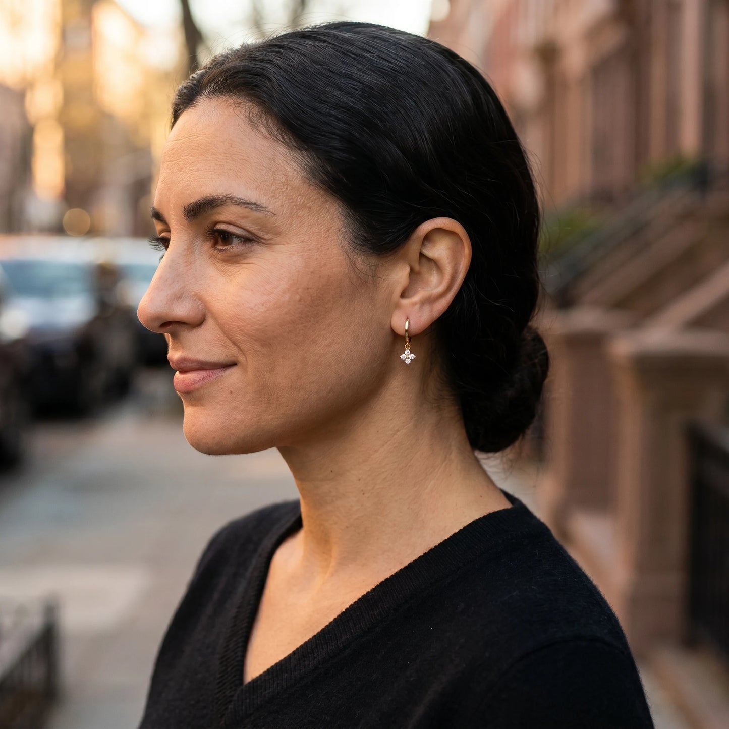 Gold petite clover huggie earrings profile editorial