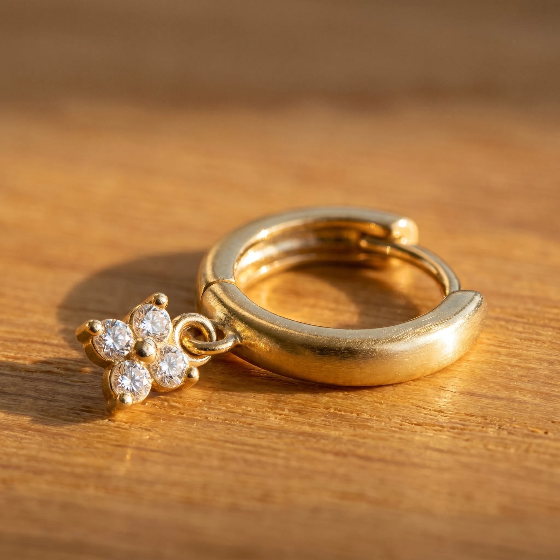 Gold petite clover huggie earring macro detail four CZ stones