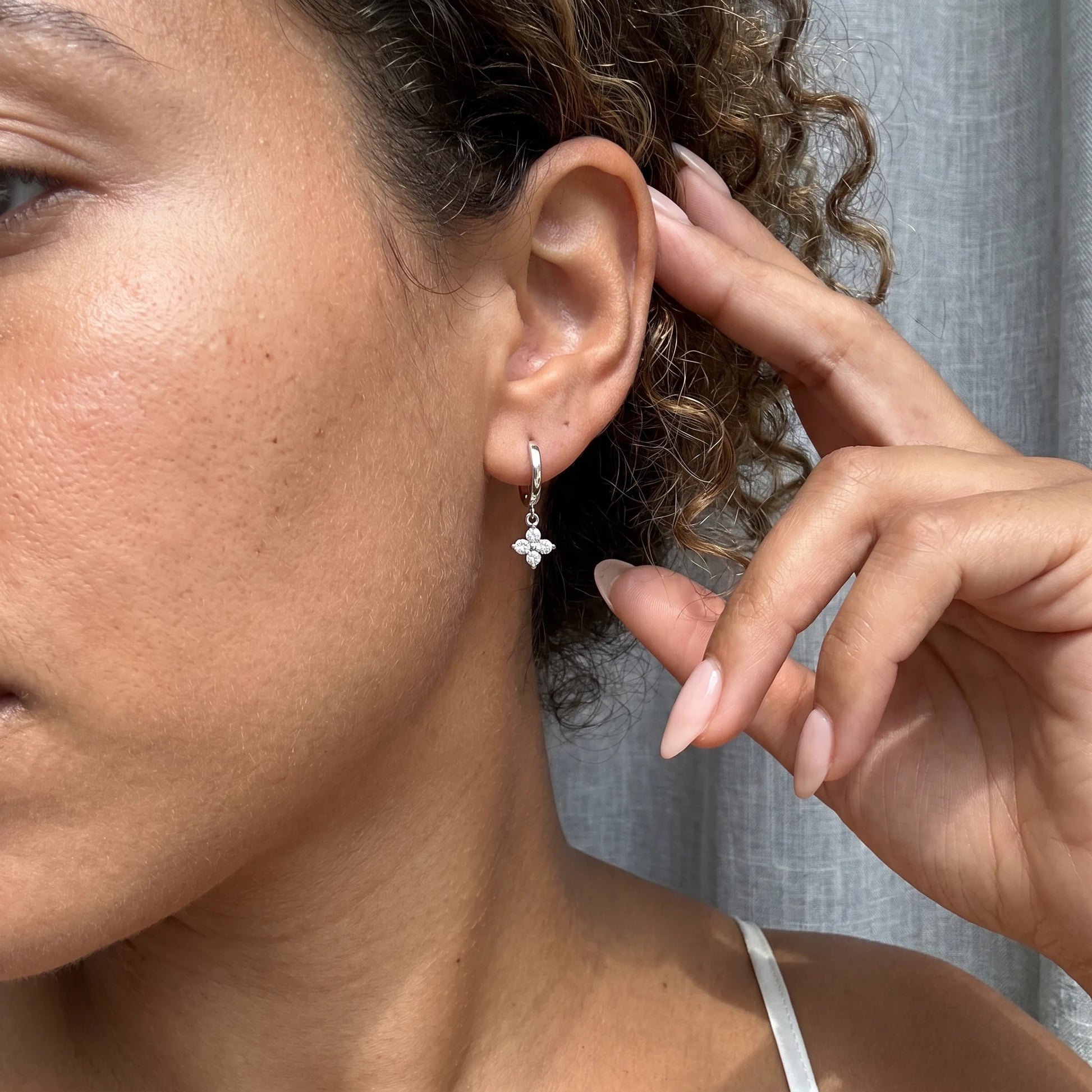 Silver petite clover huggie earrings lifestyle hand to ear
