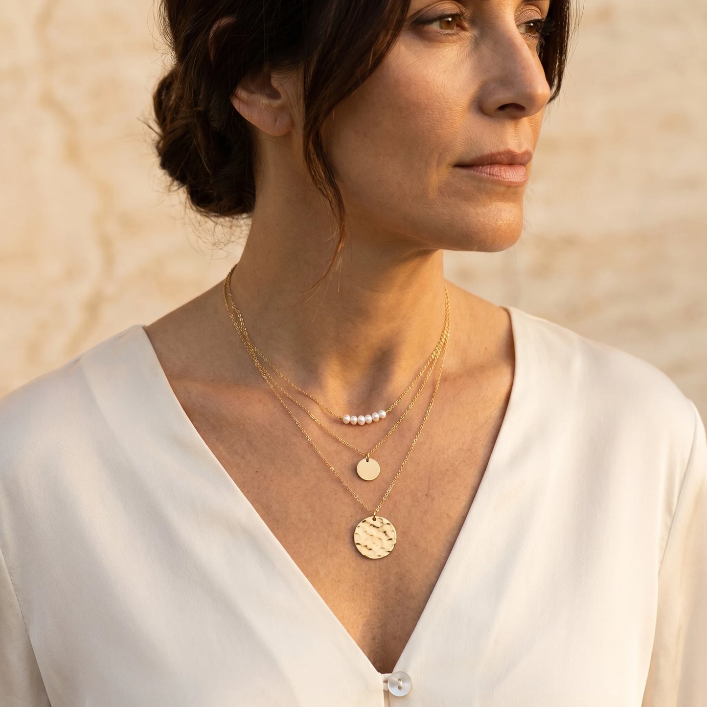 Mature woman wearing gold pearl coin layered necklace set on Italian villa terrace
