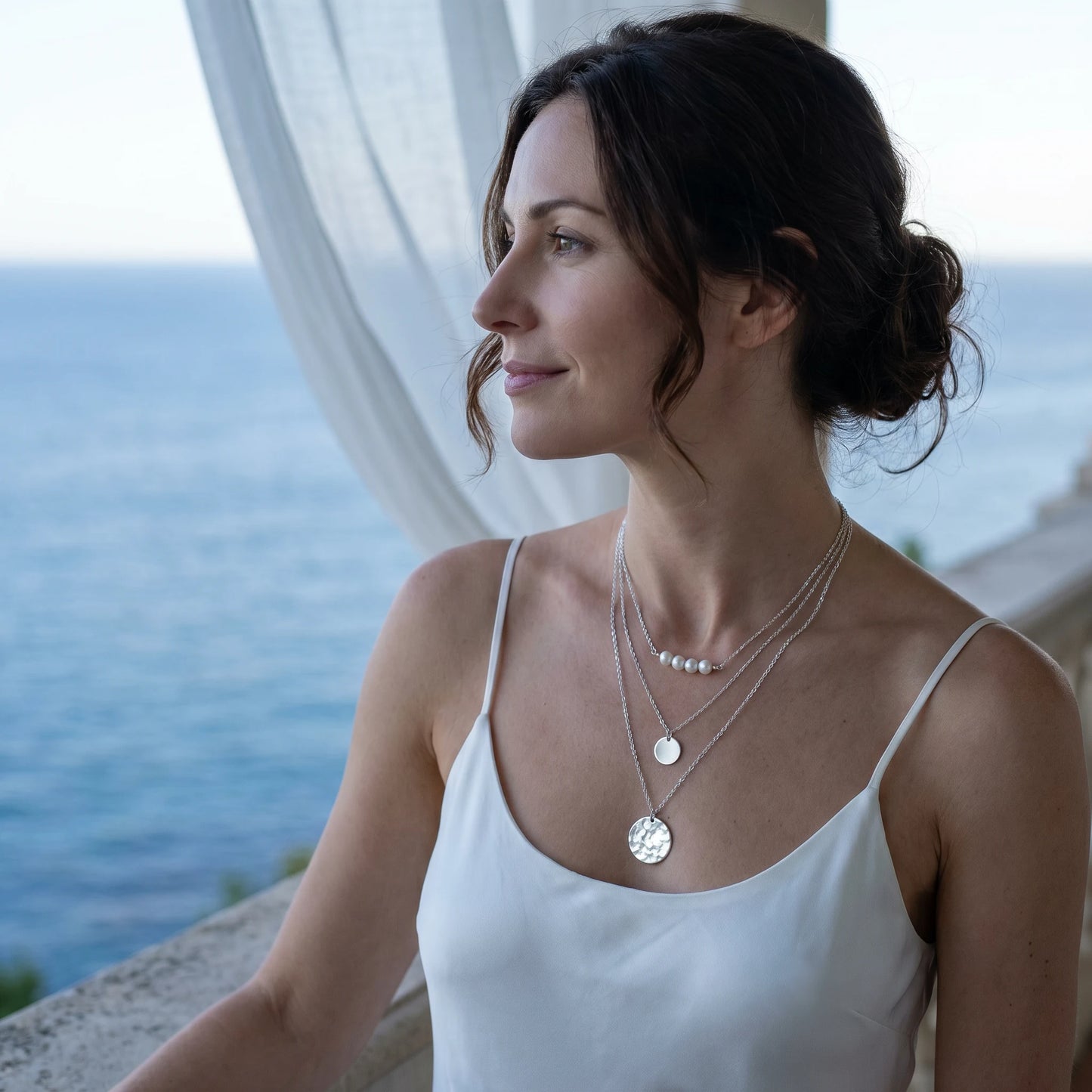 Woman profile Riviera coastal balcony wearing layered pearl coin necklace silver