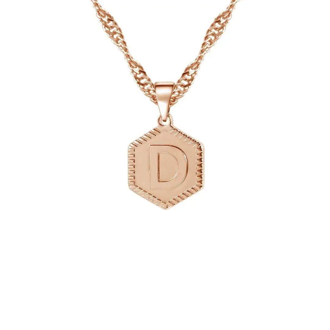 Hexagon Initial Necklace by AUREATE featuring a gold hexagon pendant with the letter D on a unique wave chain.