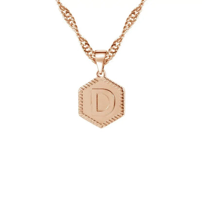 Hexagon Initial Necklace by AUREATE featuring a gold hexagon pendant with the letter D on a unique wave chain.