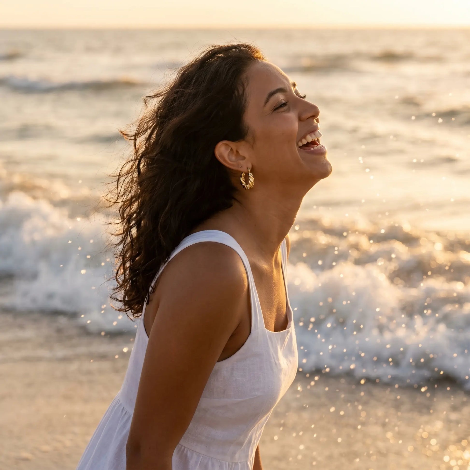 Woman on beach wearing Twisted Gold Hoop Earrings - waterproof sunset