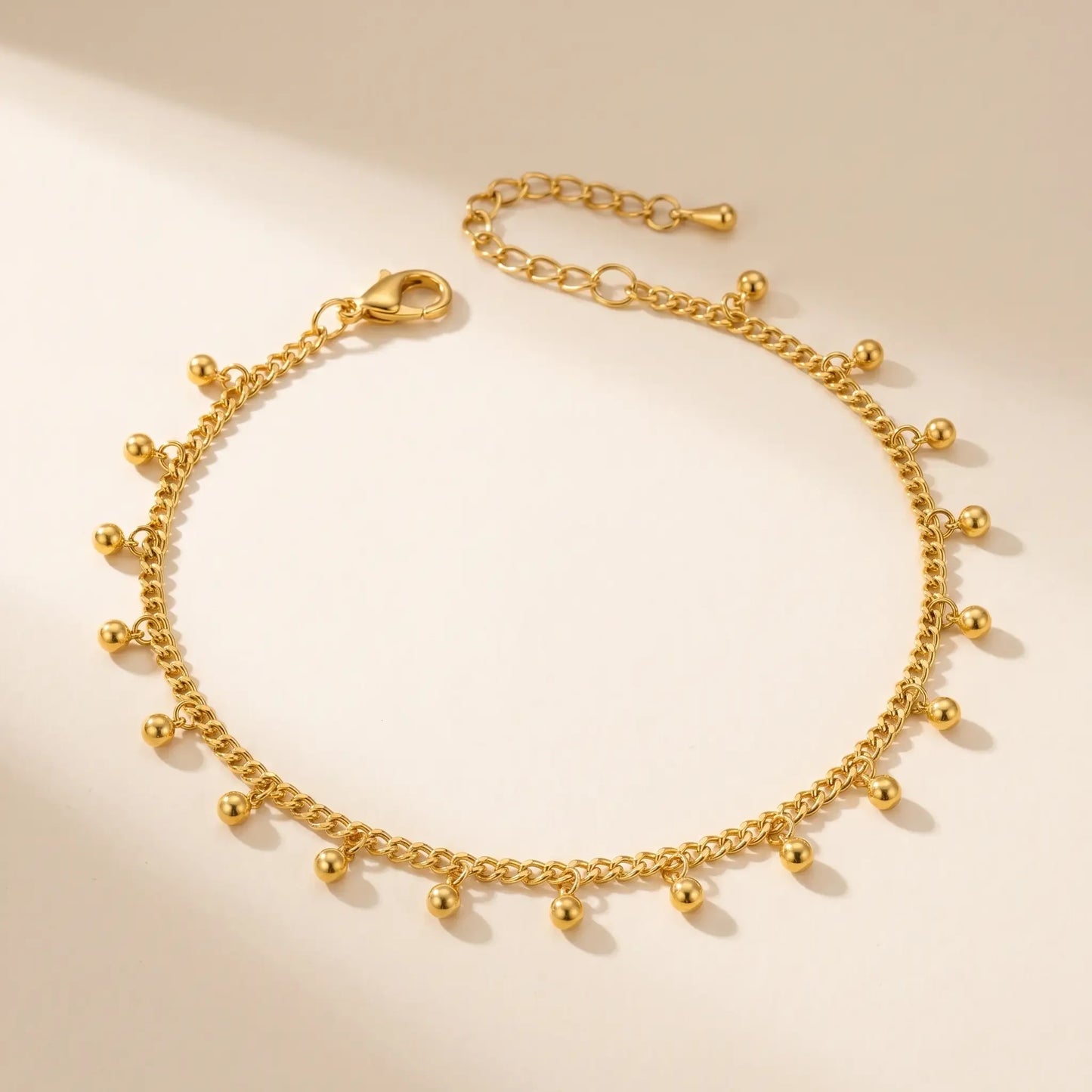 Gold drop bead anklet packshot on off-white background - fine cable chain with ball drops