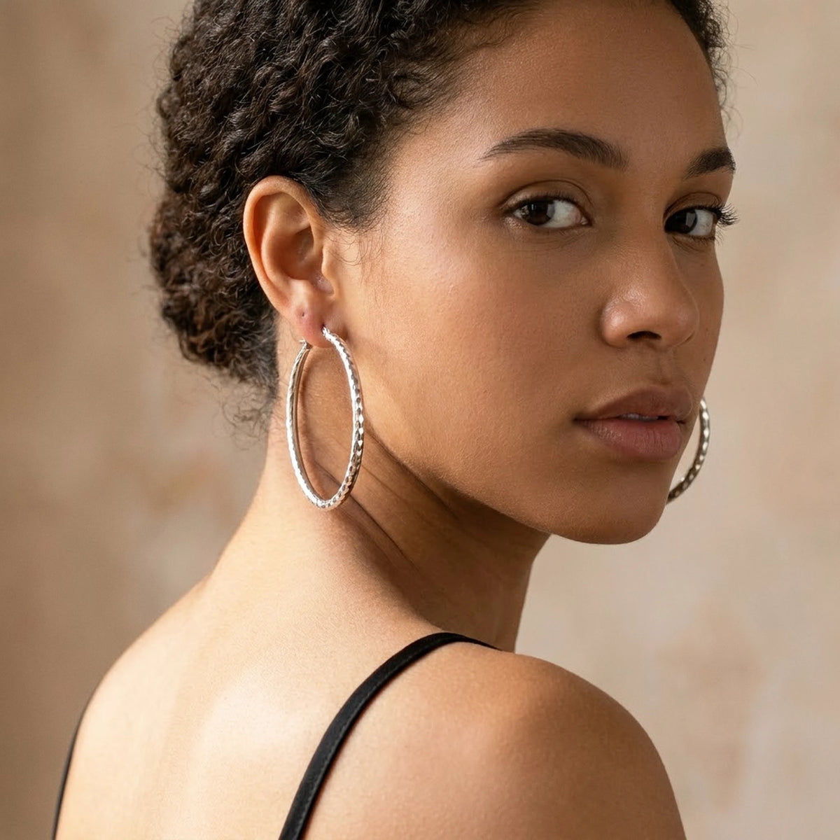 Silver tone stainless steel diamond cut large hoop earrings, worn, over the shoulder portrait | SKU: AUR-DCTHOP-S