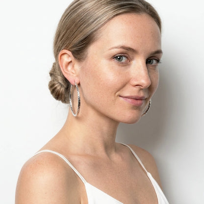 Silver tone stainless steel diamond cut large hoop earrings, worn, waist up portrait | SKU: AUR-DCTHOP-S