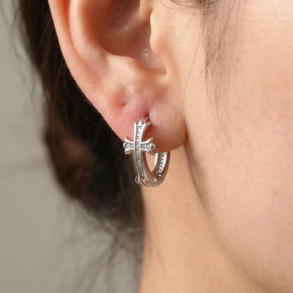 Silver tone stainless steel pave cross huggie hoop earrings, macro detail on the earlobe | SKU: AUR-CRXHUG-S